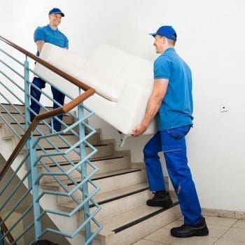 Professional movers carrying a sofa up a flight of stairs