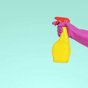 Hand wearing a rubber glove holding a spray bottle