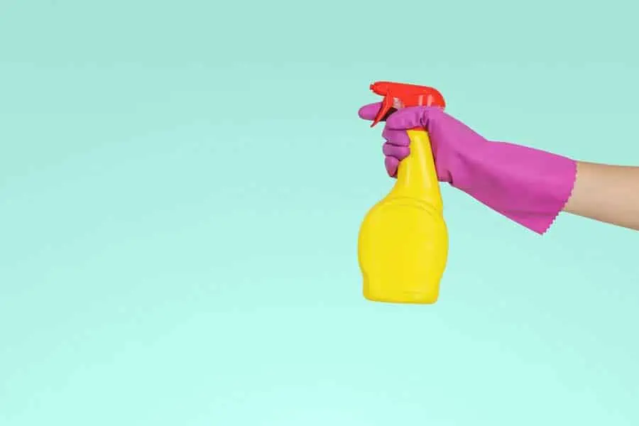 Hand wearing a rubber glove holding a spray bottle