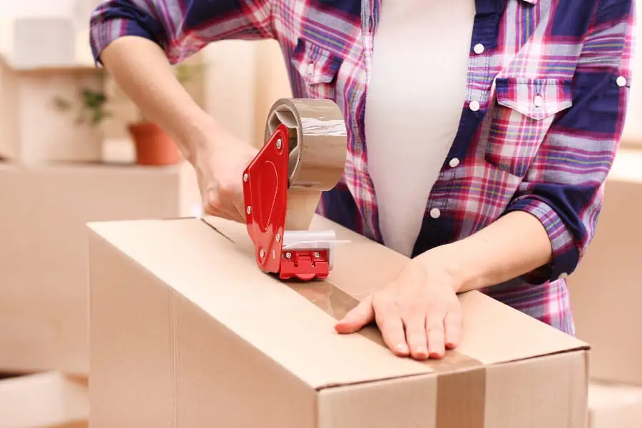 A woman taping a moving box.
