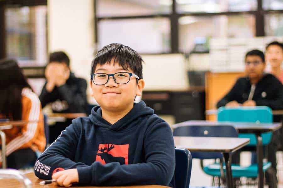 Boy sitting at a desk in a middle school classroom