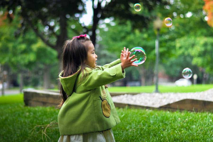 Girl playing with bubbles at a park
