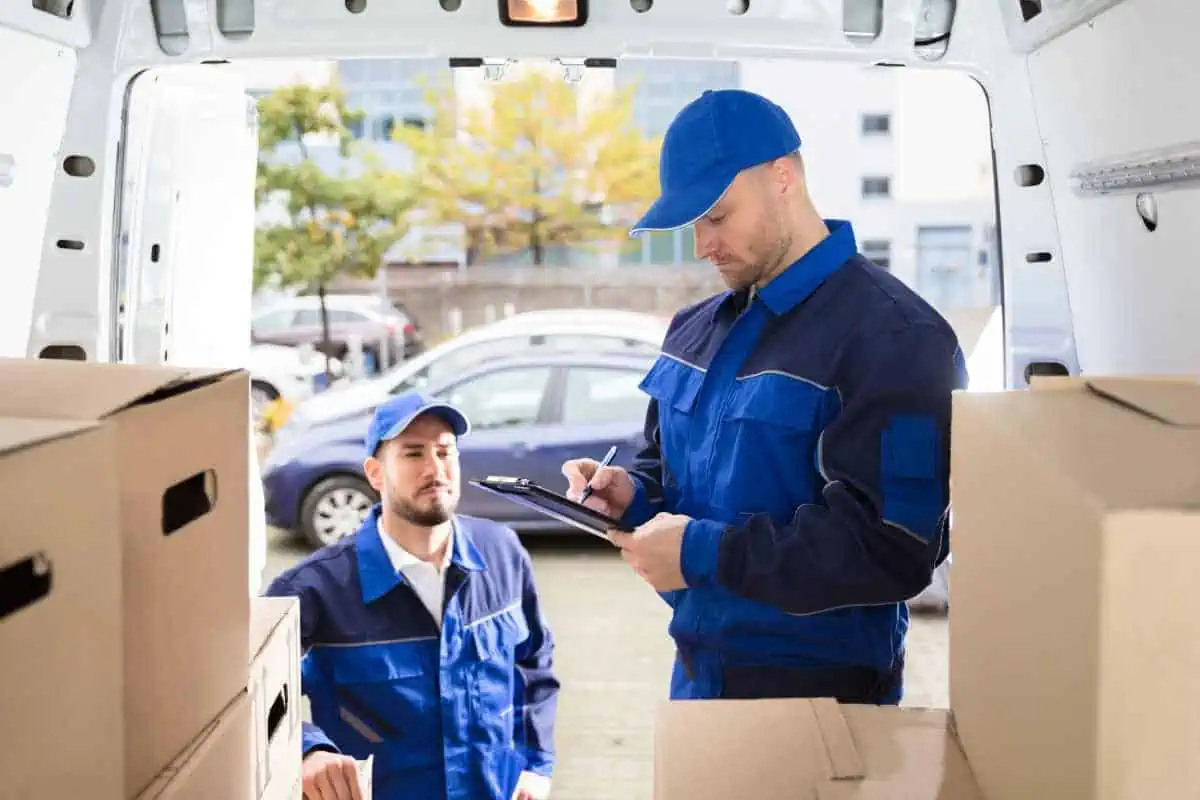 Professional movers taking inventory of items loaded into a moving truck